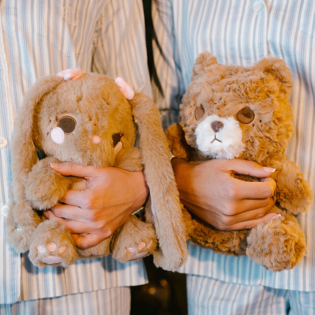 Two people in matching striped pajamas holding teddy bears.